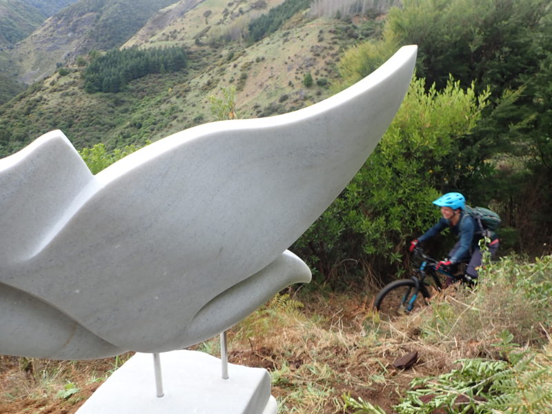 Mountain biker riding past the karearea sculpture